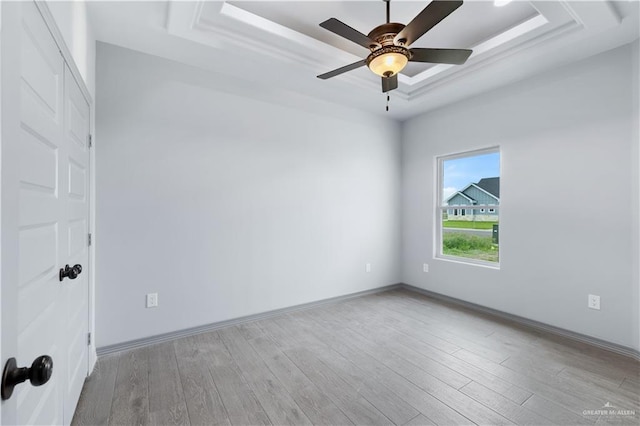 unfurnished room featuring baseboards, ceiling fan, wood finished floors, and a raised ceiling