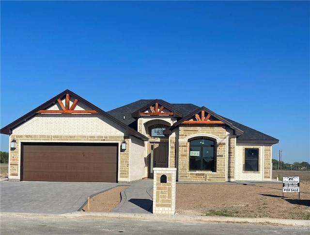 view of front of property with decorative driveway, brick siding, and an attached garage