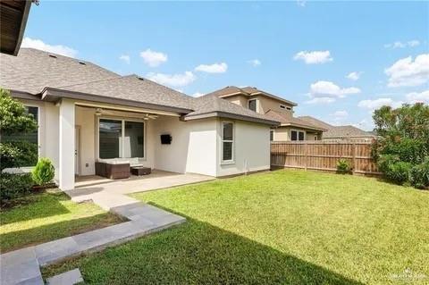 back of property with a lawn, a patio area, fence, and stucco siding