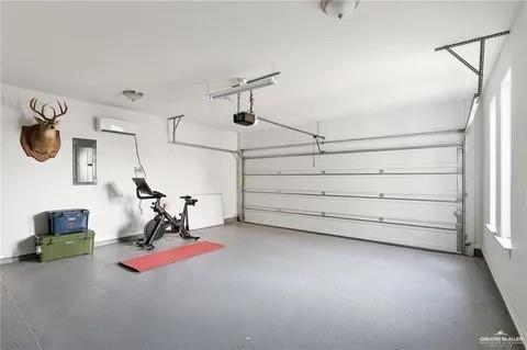 garage with a wall mounted AC, electric panel, and a garage door opener