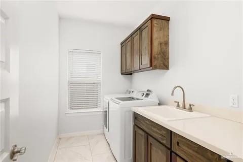 clothes washing area featuring cabinet space, baseboards, washer and clothes dryer, marble finish floor, and a sink