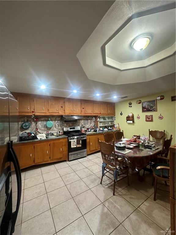 kitchen with tasteful backsplash, stainless steel range, and light tile patterned floors