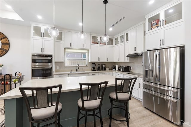 kitchen featuring a kitchen island, stainless steel appliances, white cabinets, and sink