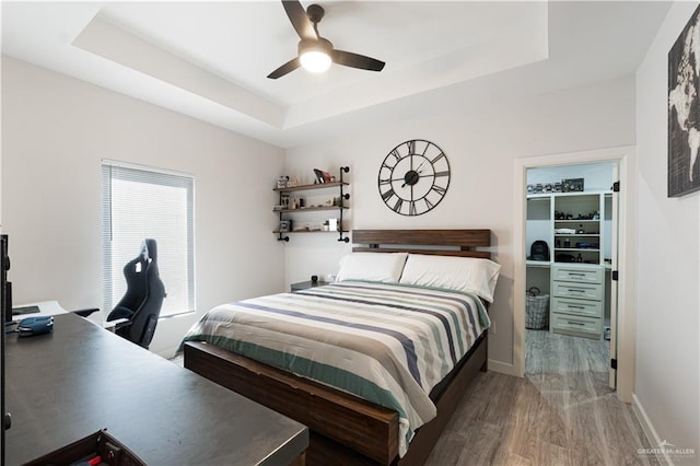 bedroom featuring ceiling fan, a raised ceiling, and wood-type flooring