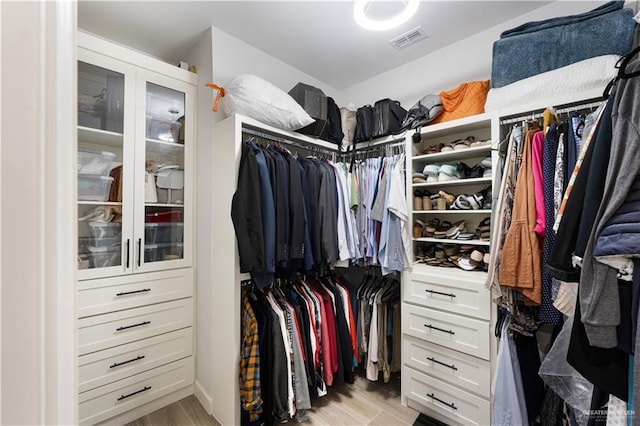 walk in closet with light hardwood / wood-style floors