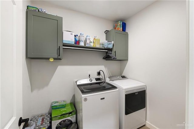 clothes washing area featuring cabinets and washer and clothes dryer