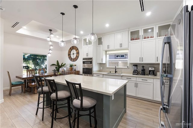 kitchen with sink, a raised ceiling, a center island, and appliances with stainless steel finishes