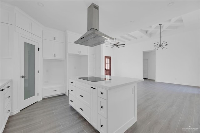 kitchen featuring beamed ceiling, island range hood, a kitchen island, and white cabinetry