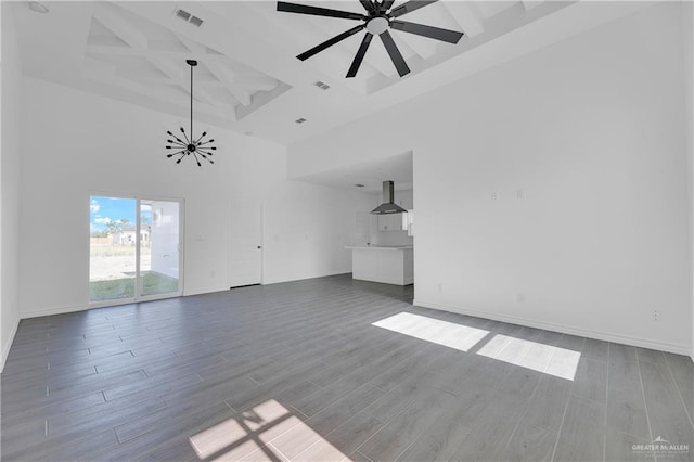 unfurnished living room featuring ceiling fan, a towering ceiling, and wood-type flooring