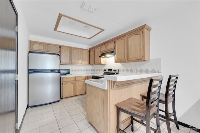 kitchen featuring visible vents, under cabinet range hood, decorative backsplash, a peninsula, and stainless steel appliances