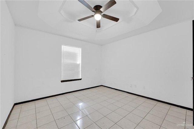 spare room featuring light tile patterned floors, baseboards, a raised ceiling, and a ceiling fan