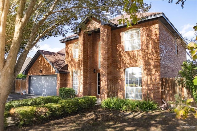 view of front of home featuring an attached garage, driveway, fence, and brick siding