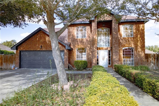 traditional-style home featuring a garage, concrete driveway, brick siding, and fence