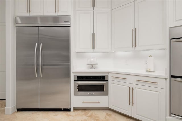 kitchen featuring built in fridge, white cabinetry, and double wall oven