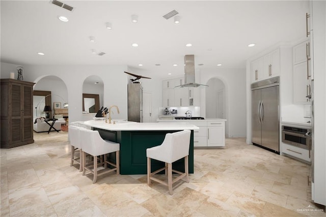 kitchen with island exhaust hood, stainless steel appliances, white cabinets, and a spacious island