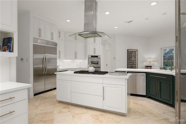 kitchen with appliances with stainless steel finishes, island range hood, a kitchen island, sink, and white cabinetry