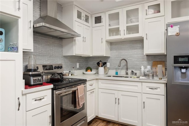 kitchen featuring appliances with stainless steel finishes, dark hardwood / wood-style flooring, sink, wall chimney range hood, and white cabinetry