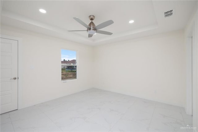 unfurnished room with a raised ceiling, visible vents, recessed lighting, a ceiling fan, and marble finish floor