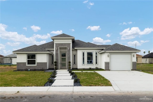 prairie-style home with stucco siding, concrete driveway, a front yard, and an attached garage