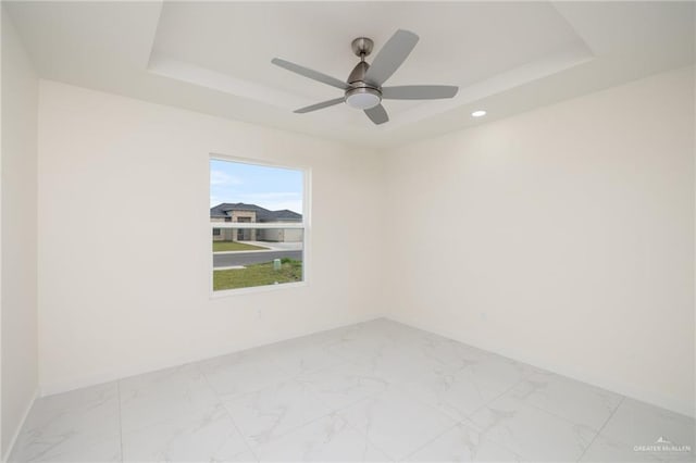 spare room featuring recessed lighting, a raised ceiling, marble finish floor, a ceiling fan, and baseboards