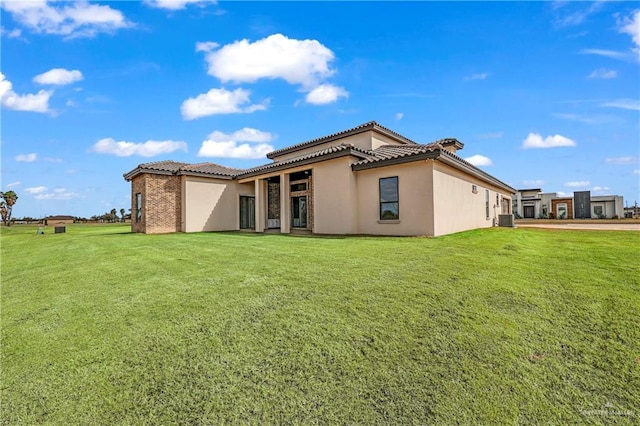 rear view of house with central AC unit and a lawn