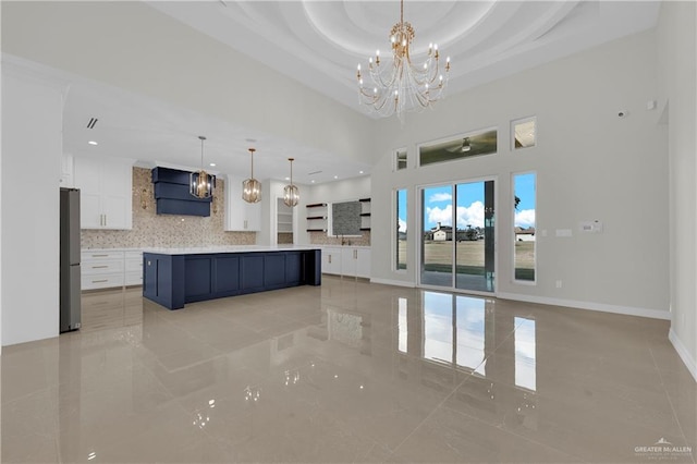 kitchen featuring pendant lighting, stainless steel refrigerator, white cabinetry, a spacious island, and decorative backsplash