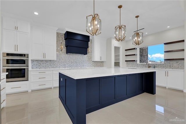 kitchen featuring decorative light fixtures, white cabinets, stainless steel double oven, wall chimney range hood, and a spacious island