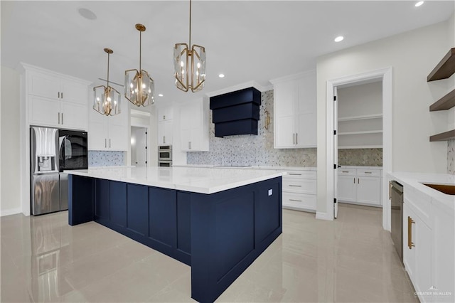 kitchen featuring pendant lighting, appliances with stainless steel finishes, white cabinetry, a spacious island, and wall chimney exhaust hood