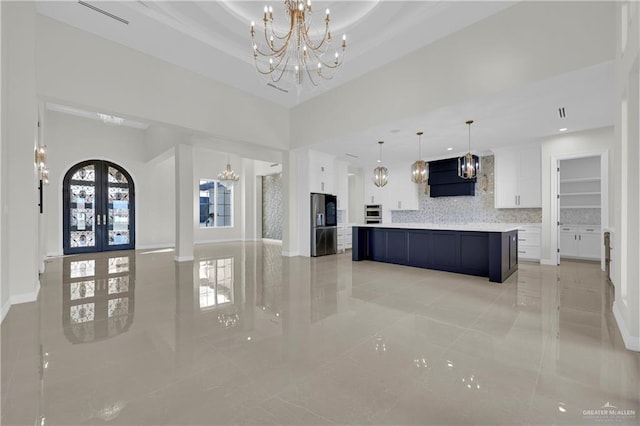 kitchen featuring white cabinetry, a large island, tasteful backsplash, and a notable chandelier