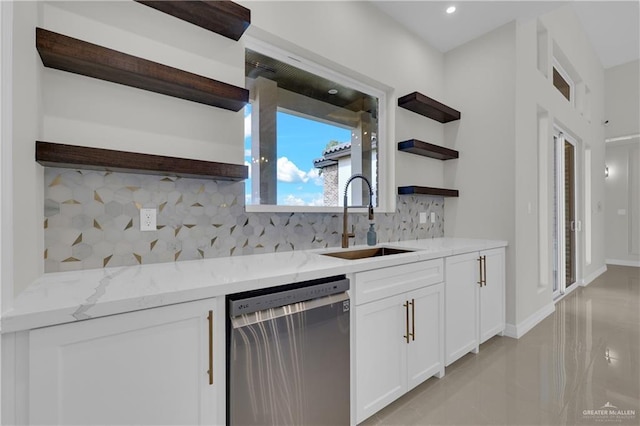 kitchen with sink, stainless steel dishwasher, white cabinets, and light stone counters