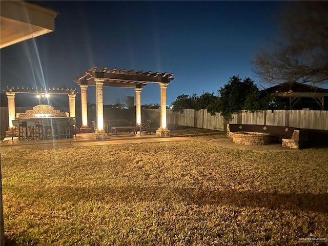 yard at night with a pergola, fence, and a patio