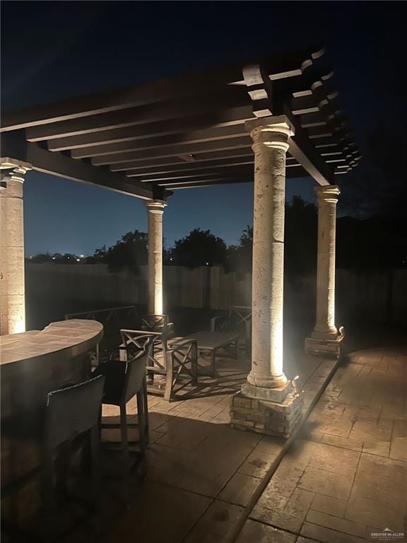 patio at night with outdoor dining area and a pergola