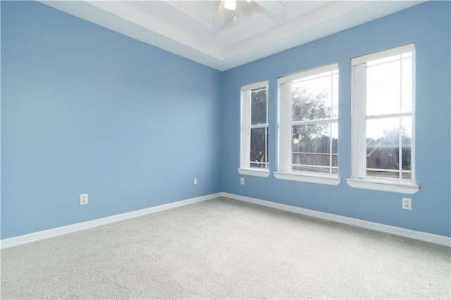 unfurnished room with ceiling fan, a raised ceiling, carpet flooring, and baseboards