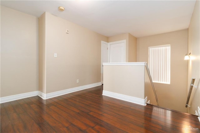 unfurnished room with baseboards and dark wood-type flooring