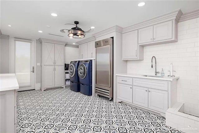 kitchen with light countertops, washer and dryer, stainless steel built in fridge, and a sink