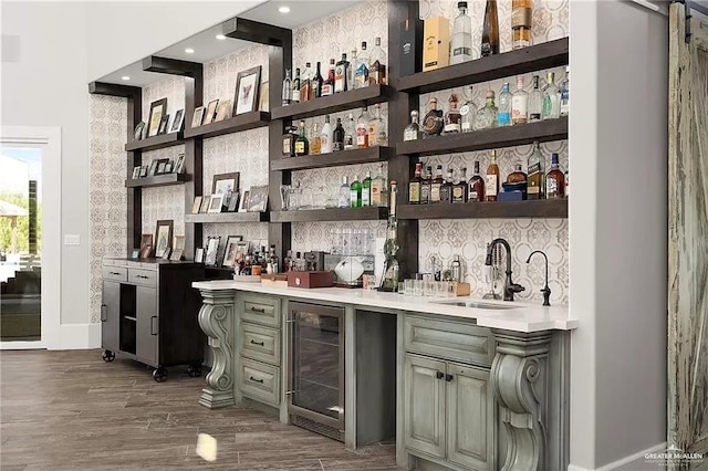 bar featuring a sink, beverage cooler, dark wood finished floors, and indoor wet bar