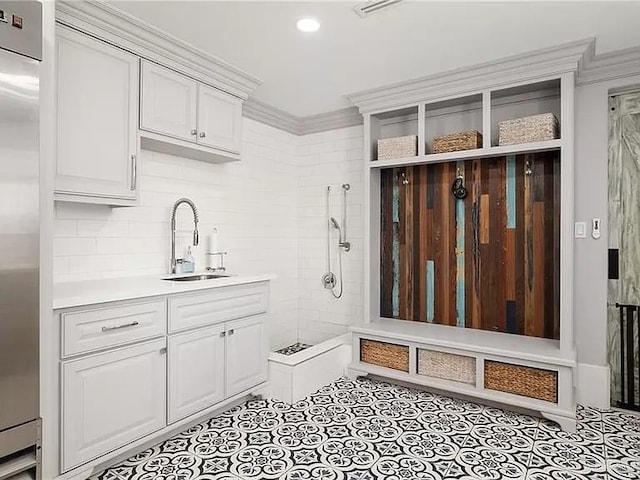 mudroom featuring ornamental molding, a sink, and light tile patterned flooring