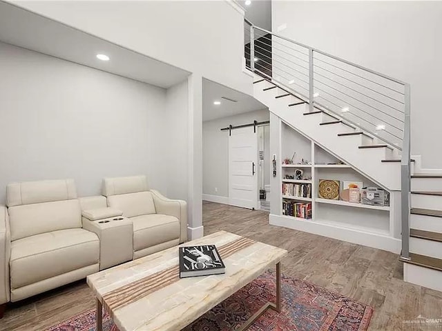 living room featuring a barn door, baseboards, wood finished floors, stairs, and a high ceiling