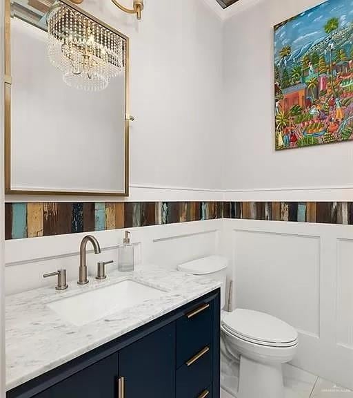 bathroom featuring toilet, wainscoting, and vanity