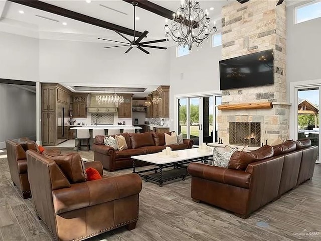 living area with a stone fireplace, wood finished floors, and beam ceiling