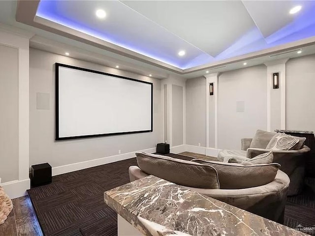 home theater featuring baseboards, a raised ceiling, and recessed lighting