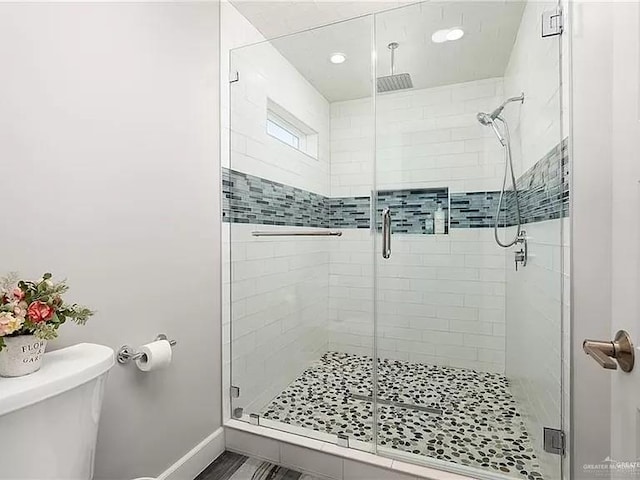 bathroom with a shower stall, toilet, and baseboards