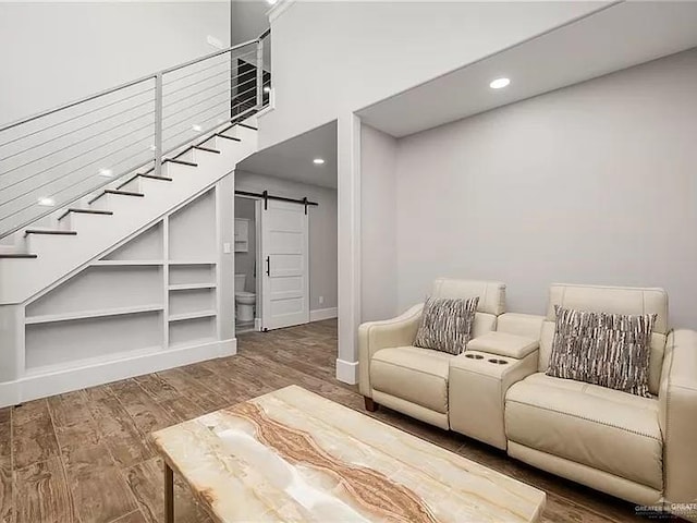 living room featuring stairs, wood finished floors, a high ceiling, and a barn door