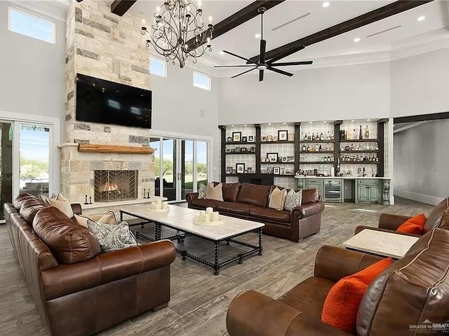 living room featuring beamed ceiling, a fireplace, a towering ceiling, and bar