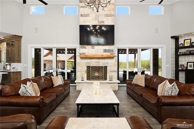 living area featuring dark wood-style floors, a wealth of natural light, french doors, and a stone fireplace