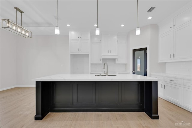 kitchen with hanging light fixtures, a sink, and white cabinets