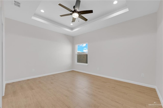 spare room featuring ceiling fan, recessed lighting, baseboards, light wood-type flooring, and a raised ceiling