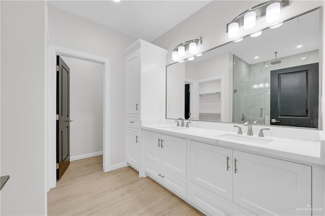 bathroom featuring a shower stall, a spacious closet, a sink, and wood finished floors