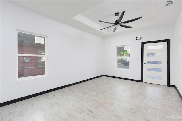 unfurnished room featuring ceiling fan, a tray ceiling, and light hardwood / wood-style flooring