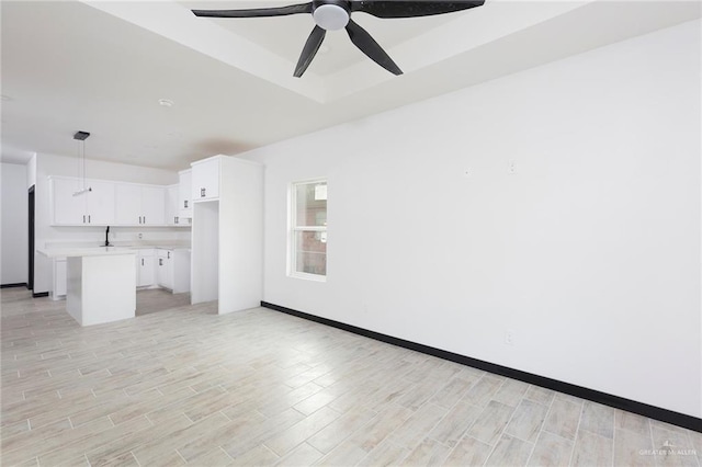 unfurnished living room with a raised ceiling and ceiling fan